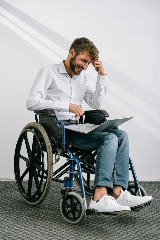 pexels-photo-8127976-8127976 Man in wheelchair working on a laptop indoors, showcasing accessibility and technology.